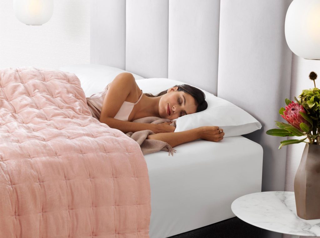 Model sleeps comfortably on Sealy mattress with flowers beside bed