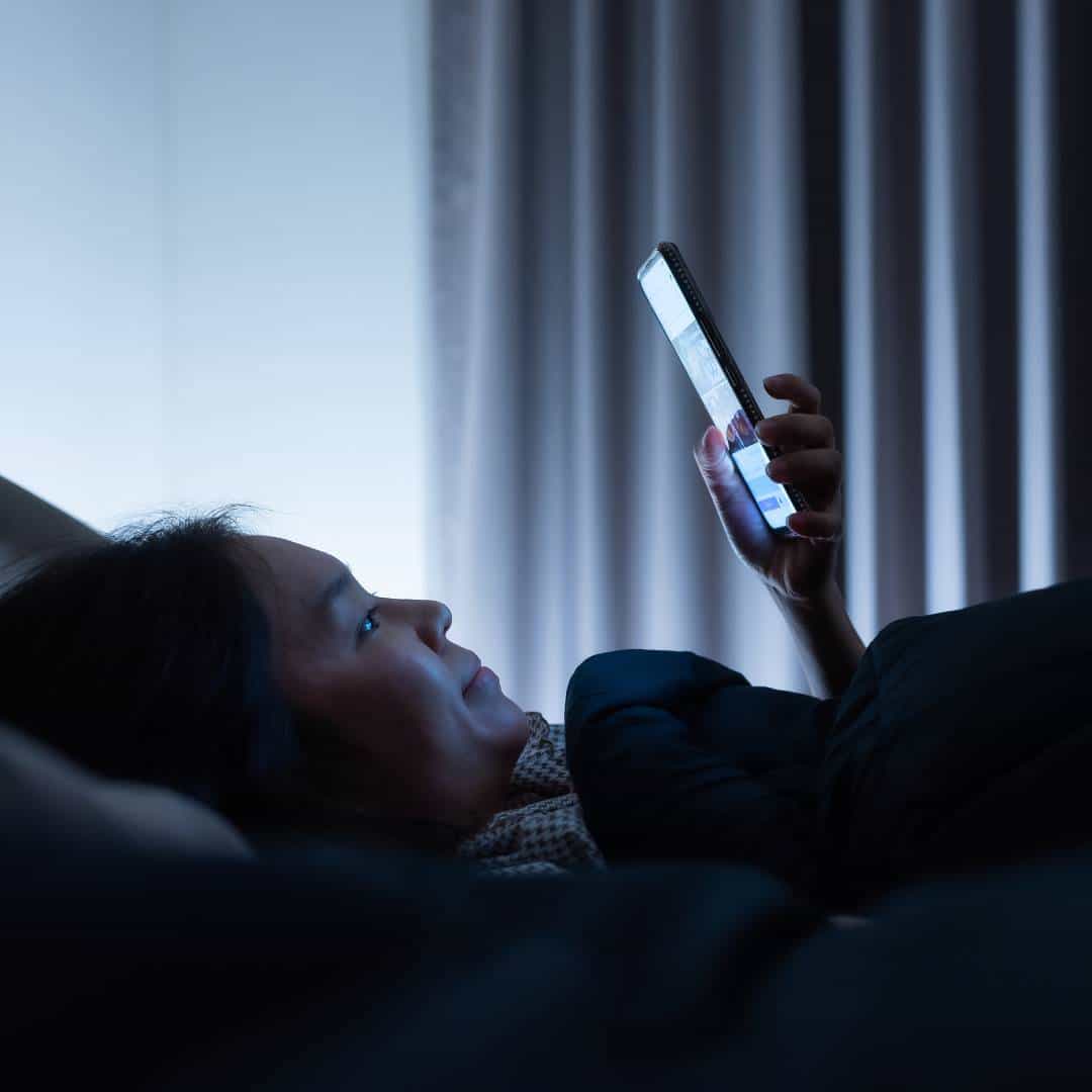 Woman using phone in bed