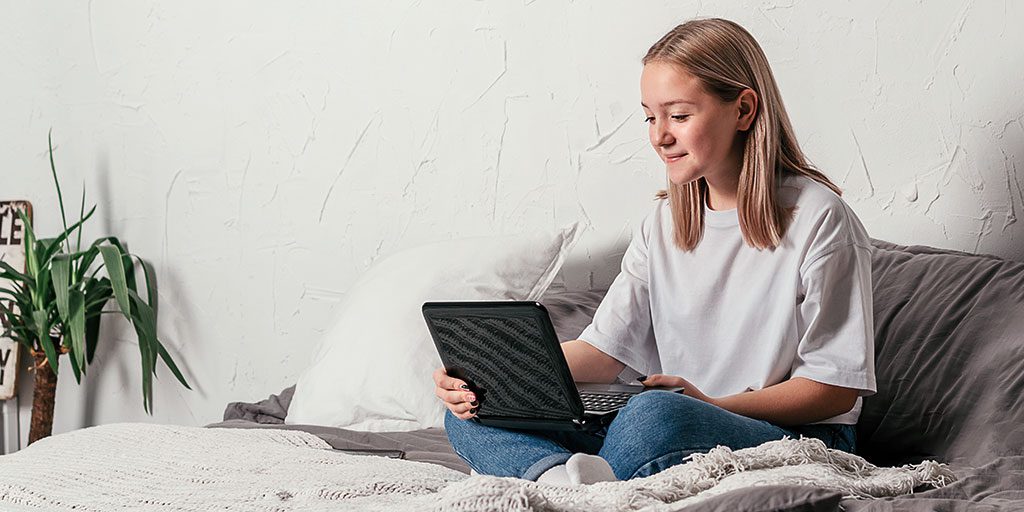 teenager in bed on laptop