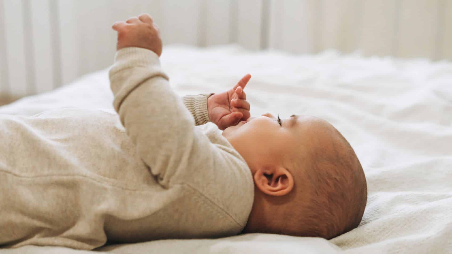 Baby in cot lying on back