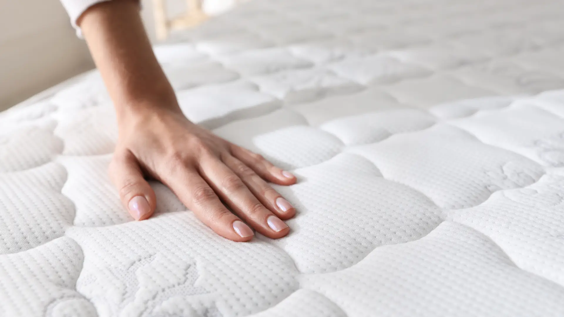 Woman's hand on mattress surface